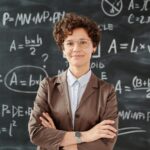 Portrait of a teacher standing in front of a blackboard full of mathematical equations.