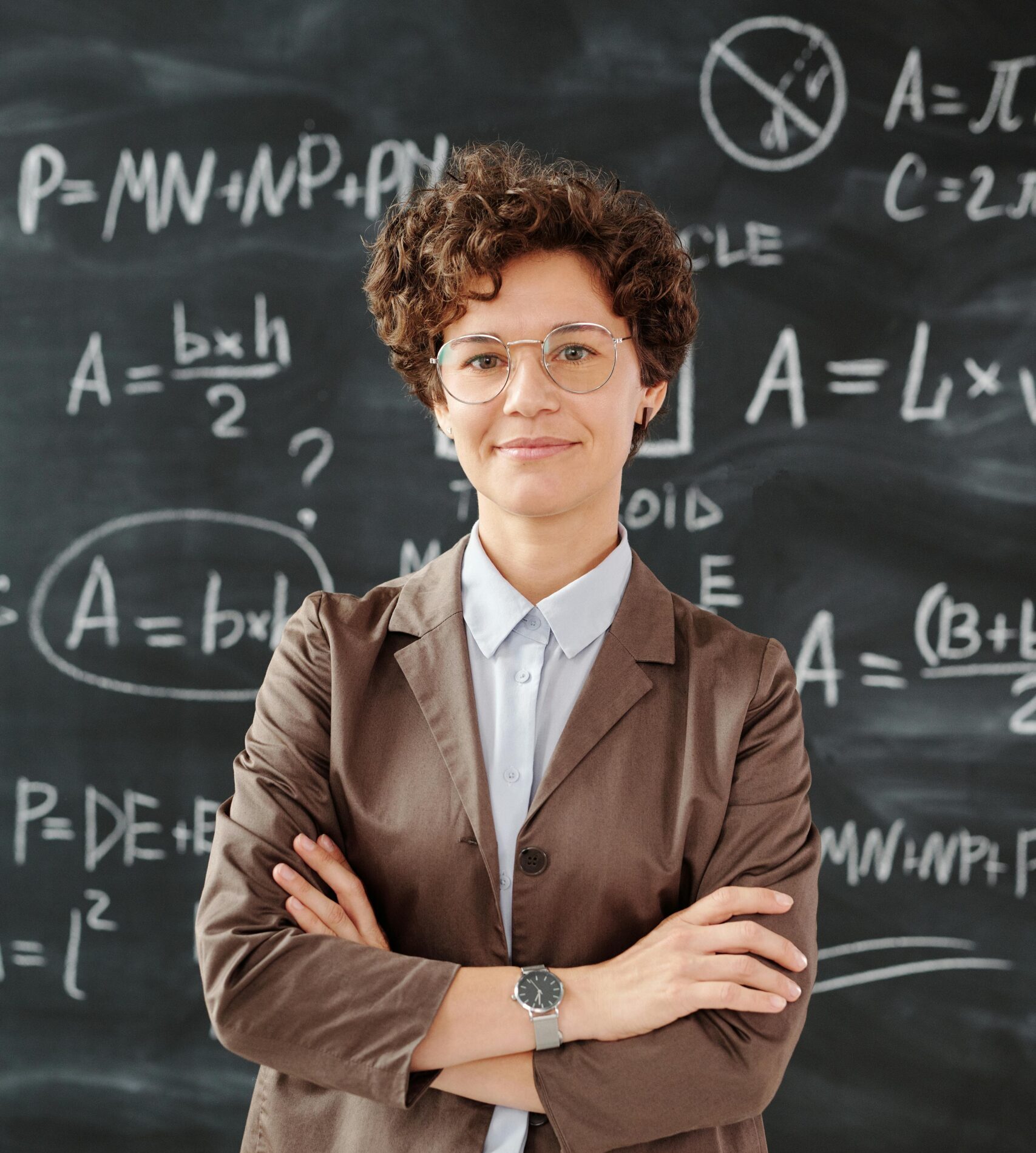 Portrait of a teacher standing in front of a blackboard full of mathematical equations.