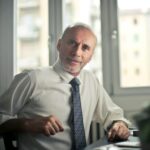A mature man in professional attire smiling in an office setting.