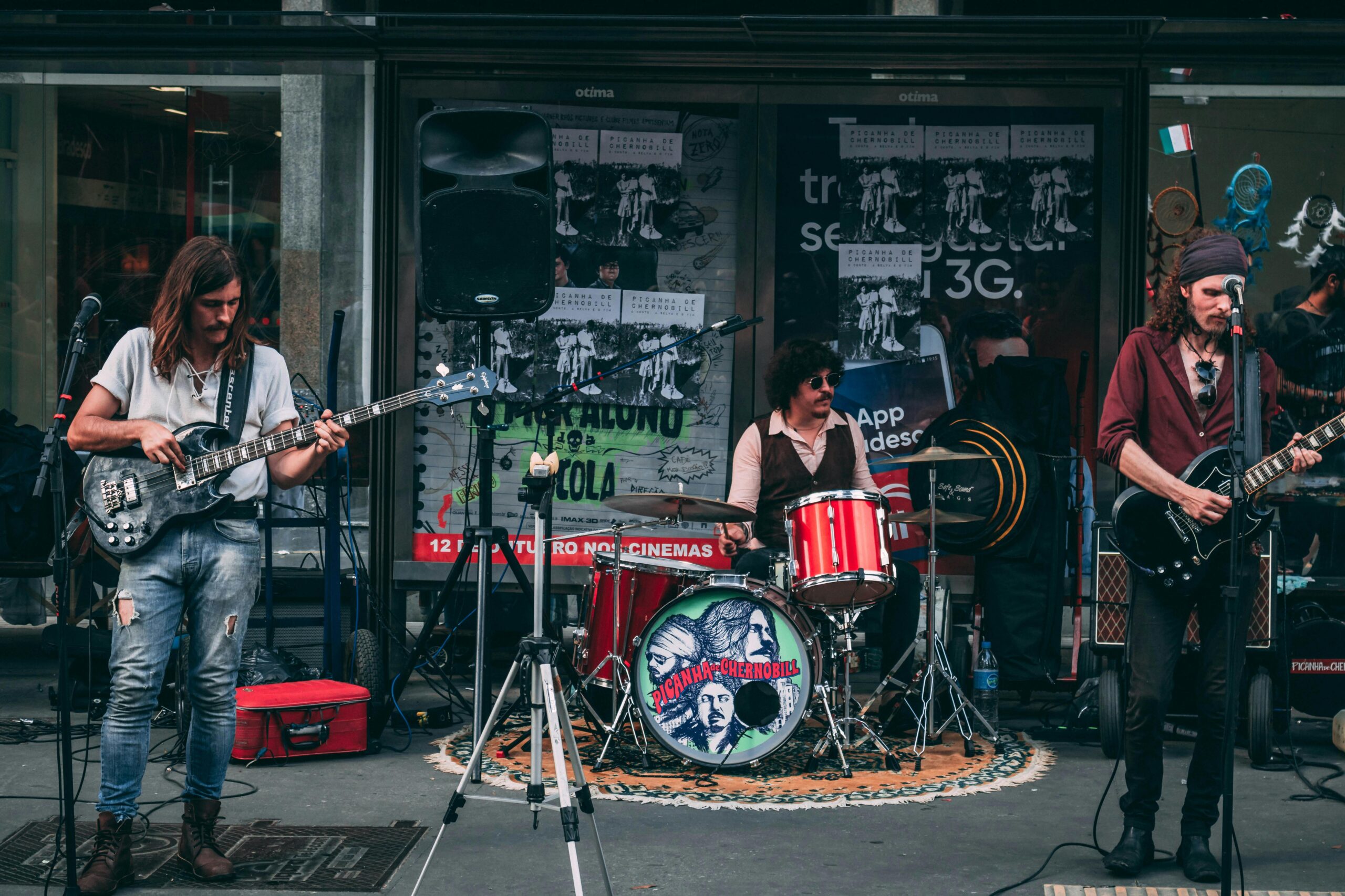 Indie band performing live on a street with guitarists and drummer entertaining the crowd.